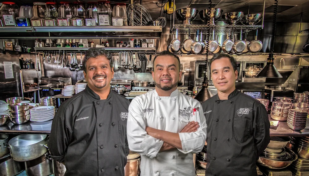 Executive chef and two culinary team members posing confidently in The Bell Tower on 34th's professional kitchen.