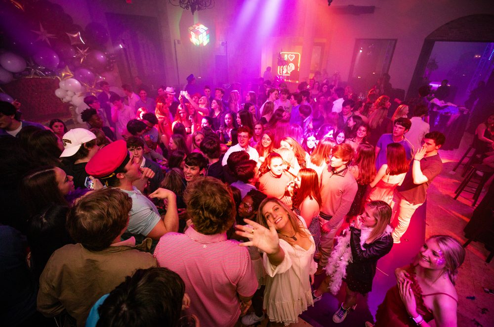 Students dancing under red and pink stage lighting at a school dance at The Bell Tower on 34th, Houston, TX.